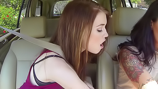Two girls are in the car and they are licking one another well